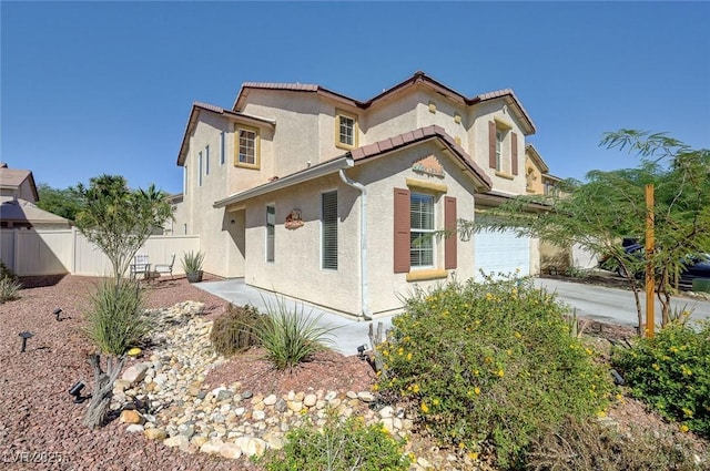 view of front of home with a garage, driveway, stucco siding, and fence