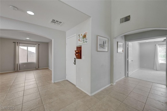 interior space with visible vents, baseboards, arched walkways, and light tile patterned floors