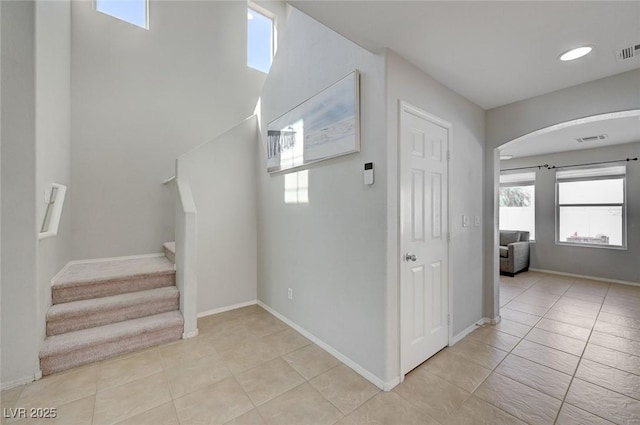 interior space with arched walkways, baseboards, tile patterned flooring, and visible vents