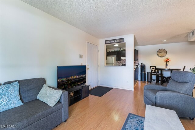 living area with a textured ceiling, visible vents, and wood finished floors