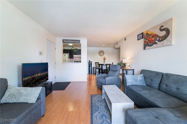 living room featuring a textured ceiling, visible vents, and light wood-style flooring