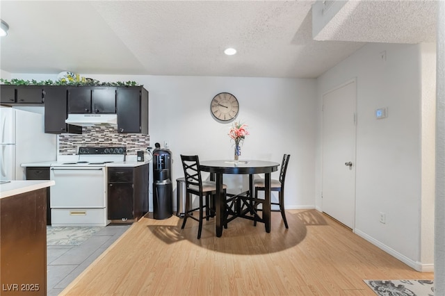 dining room featuring baseboards, light wood-type flooring, a textured ceiling, and recessed lighting