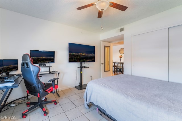 bedroom featuring light tile patterned flooring, visible vents, a ceiling fan, and baseboards