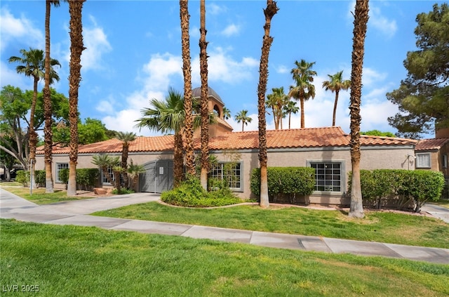 mediterranean / spanish house with concrete driveway, a front lawn, stucco siding, and a tiled roof