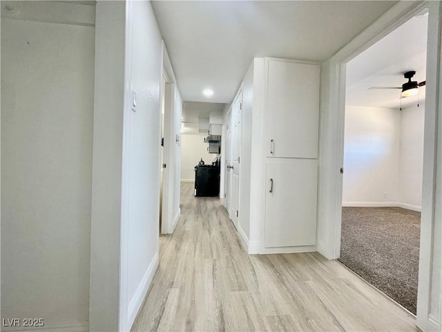 hallway with light wood-type flooring and baseboards