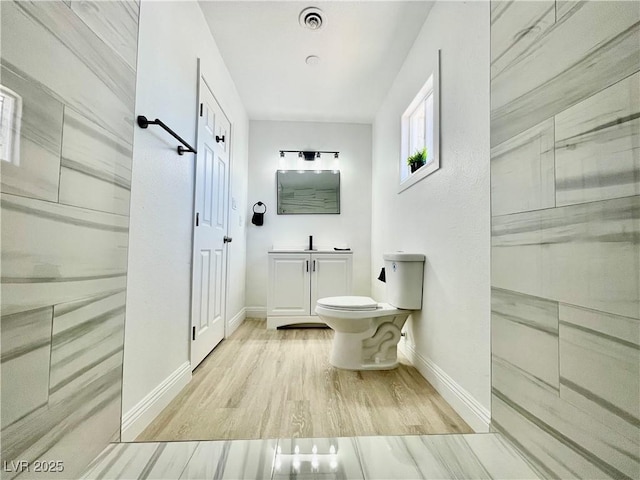 bathroom featuring toilet, vanity, baseboards, and visible vents