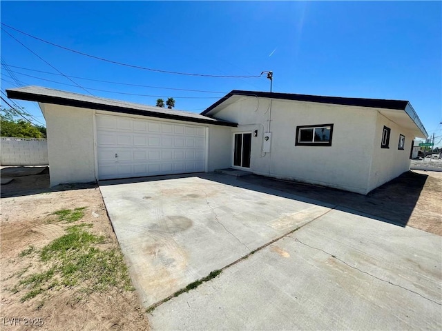 ranch-style house with concrete driveway, fence, a garage, and stucco siding