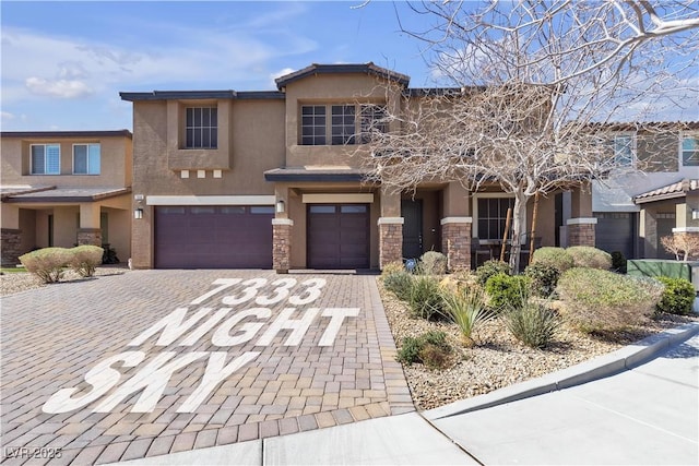 view of front of property featuring a garage, stucco siding, decorative driveway, and stone siding
