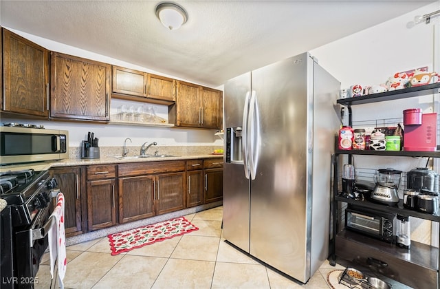 4630 Gabriel Dr, Las Vegas, NV 89121 - kitchen featuring a textured ceiling, light tile patterned flooring, light stone countertops, stainless steel appliances, and a sink