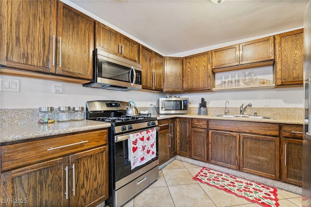 4630 Gabriel Dr, Las Vegas, NV 89121 - kitchen with appliances with stainless steel finishes, light tile patterned floors, a sink, and light stone countertops