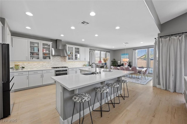 8440 Footpath St, Las Vegas, NV 89166 - kitchen with wall chimney exhaust hood, a sink, stainless steel oven, freestanding refrigerator, and a kitchen breakfast bar