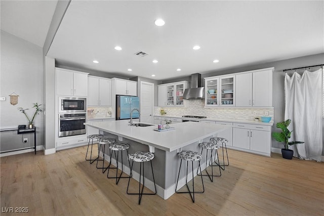 8440 Footpath St, Las Vegas, NV 89166 - kitchen featuring stainless steel appliances, wall chimney range hood, a sink, a breakfast bar, and tasteful backsplash