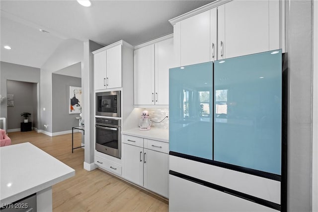 8440 Footpath St, Las Vegas, NV 89166 - kitchen with stainless steel oven, freestanding refrigerator, built in microwave, light wood-style flooring, and light countertops