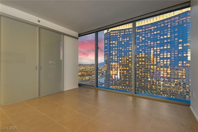 spare room with expansive windows, a city view, and tile patterned flooring