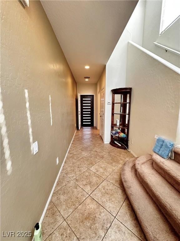 corridor with baseboards and light tile patterned floors