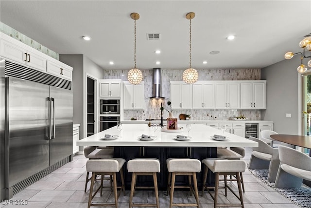 257 Elder View Dr, Las Vegas, NV 89138 - kitchen with stainless steel appliances, wall chimney exhaust hood, tasteful backsplash, white cabinetry, and light countertops