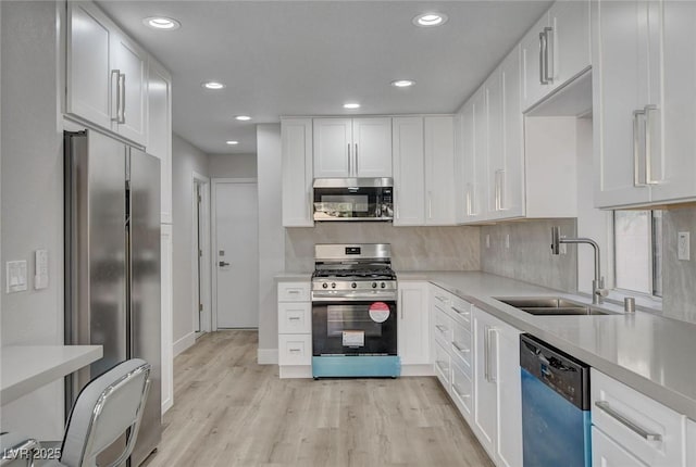 2212 Warm Walnut Dr, Las Vegas, NV 89134 - kitchen with stainless steel appliances, a sink, light wood-style flooring, white cabinetry, and recessed lighting