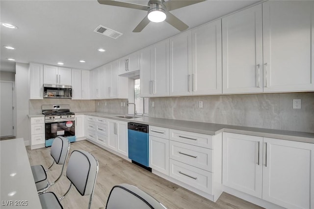 2212 Warm Walnut Dr, Las Vegas, NV 89134 - kitchen featuring appliances with stainless steel finishes, a sink, white cabinetry, light wood-type flooring, and decorative backsplash
