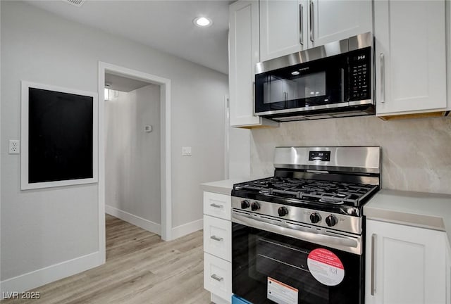 2212 Warm Walnut Dr, Las Vegas, NV 89134 - kitchen featuring appliances with stainless steel finishes, light wood-style floors, light countertops, baseboards, and white cabinetry