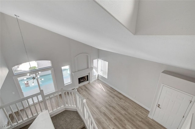2212 Warm Walnut Dr, Las Vegas, NV 89134 - unfurnished living room with a chandelier, light wood finished floors, lofted ceiling, baseboards, and a fireplace