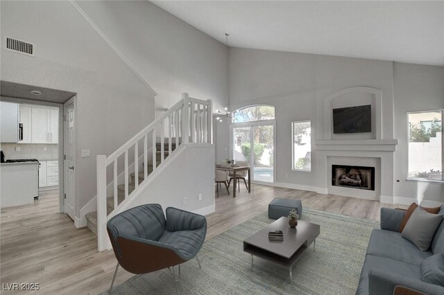 2212 Warm Walnut Dr, Las Vegas, NV 89134 - living room featuring stairway, healthy amount of natural light, light wood-type flooring, high vaulted ceiling, and a fireplace