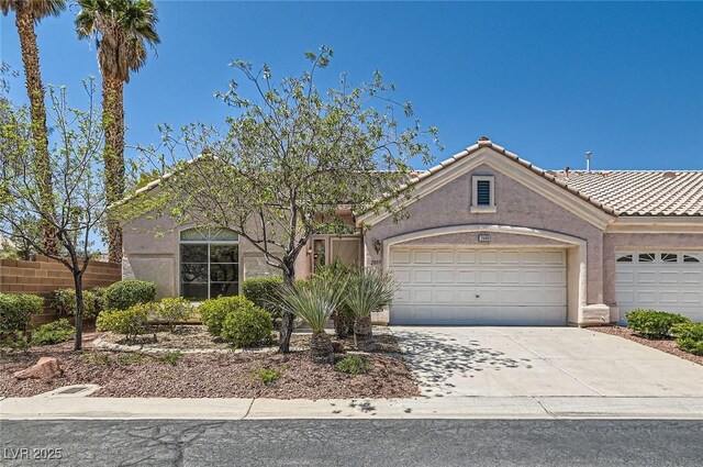 view of front of home featuring a garage, a tiled roof, concrete driveway, and stucco siding