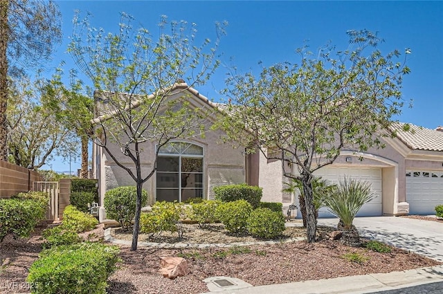 view of front facade with fence, stucco siding, an attached garage, and driveway