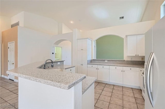 kitchen featuring light tile patterned floors, freestanding refrigerator, a sink, and visible vents
