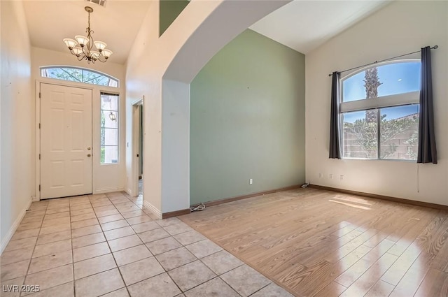 foyer with a healthy amount of sunlight, arched walkways, lofted ceiling, and a notable chandelier