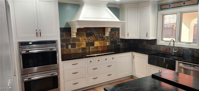 5312 Manuel Dr, Las Vegas, NV 89149 - kitchen featuring premium range hood, a sink, stainless steel appliances, white cabinetry, and dark countertops