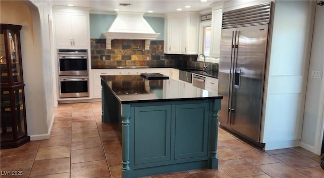 5312 Manuel Dr, Las Vegas, NV 89149 - kitchen with white cabinetry, backsplash, a center island, custom range hood, and appliances with stainless steel finishes
