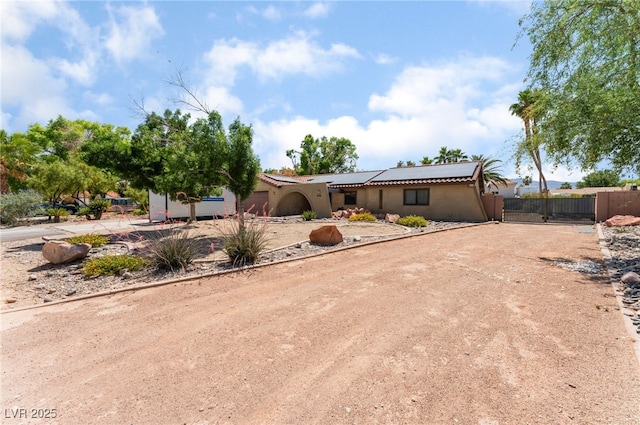 5312 Manuel Dr, Las Vegas, NV 89149 - view of front of property featuring roof mounted solar panels, a gate, stucco siding, and dirt driveway
