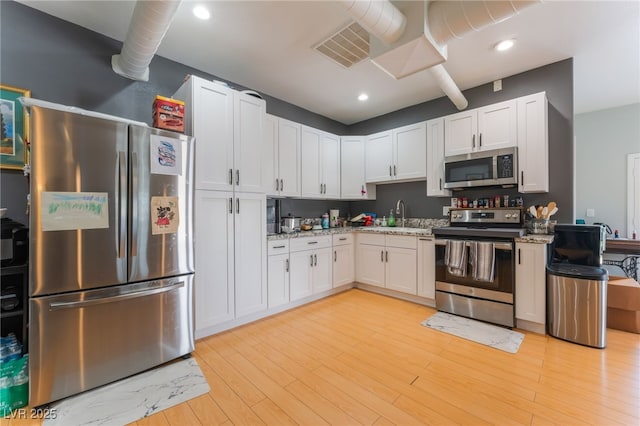 5312 Manuel Dr, Las Vegas, NV 89149 - kitchen with stainless steel appliances, a sink, white cabinets, light stone counters, and recessed lighting