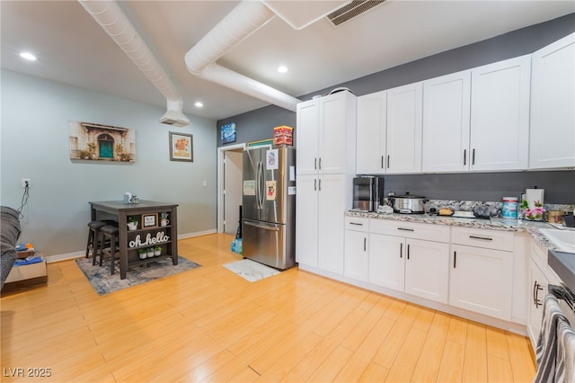 5312 Manuel Dr, Las Vegas, NV 89149 - kitchen featuring freestanding refrigerator, white cabinetry, recessed lighting, light wood finished floors, and light stone countertops