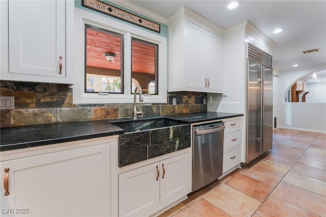 5312 Manuel Dr, Las Vegas, NV 89149 - kitchen with stainless steel appliances, a sink, dark countertops, decorative backsplash, and white cabinets