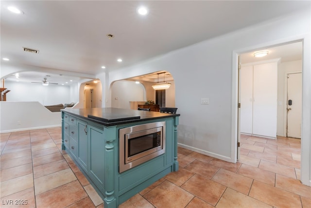 5312 Manuel Dr, Las Vegas, NV 89149 - kitchen featuring stainless steel microwave, arched walkways, dark countertops, ceiling fan, and light tile patterned floors