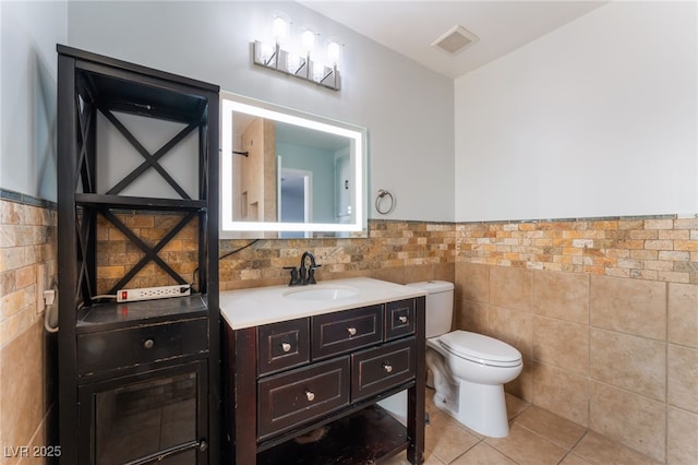 5312 Manuel Dr, Las Vegas, NV 89149 - bathroom featuring tile walls, vanity, toilet, tile patterned floors, and a wainscoted wall