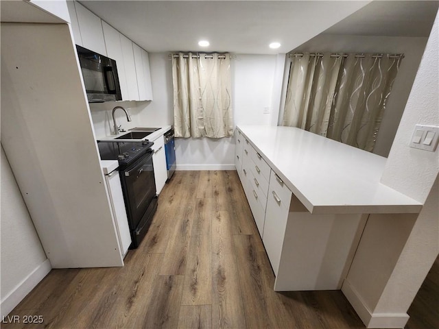 4981 River Glen Dr Unit 63, Las Vegas, NV 89103 - kitchen featuring white cabinetry, black appliances, wood finished floors, a sink, and baseboards