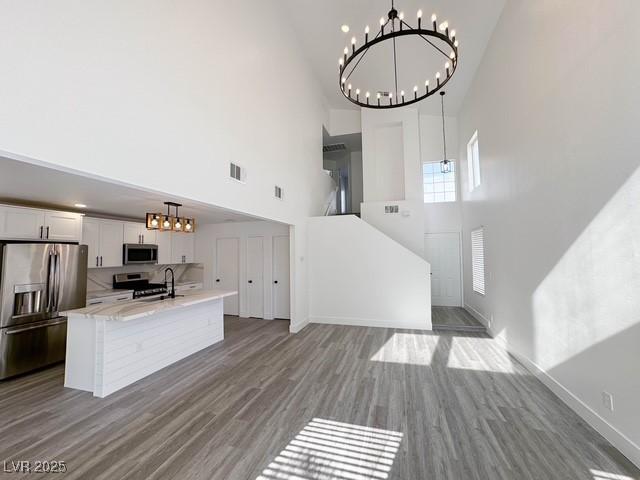 3686 Lincoln Rd, Las Vegas, NV 89115 - kitchen with a towering ceiling, stainless steel appliances, an inviting chandelier, wood finished floors, and a center island with sink