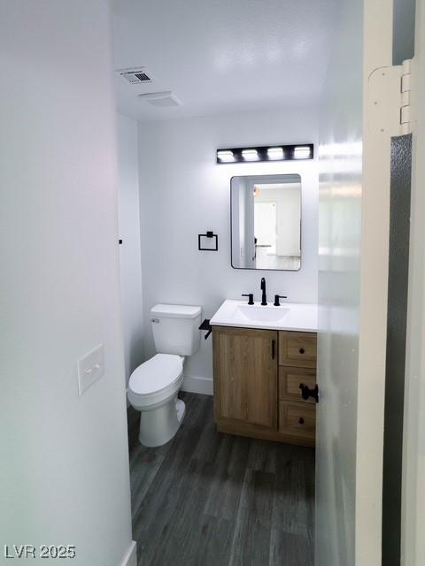 3686 Lincoln Rd, Las Vegas, NV 89115 - half bathroom featuring wood finished floors, visible vents, toilet, vanity, and baseboards