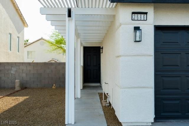 3686 Lincoln Rd, Las Vegas, NV 89115 - view of exterior entry with a garage, stucco siding, and fence