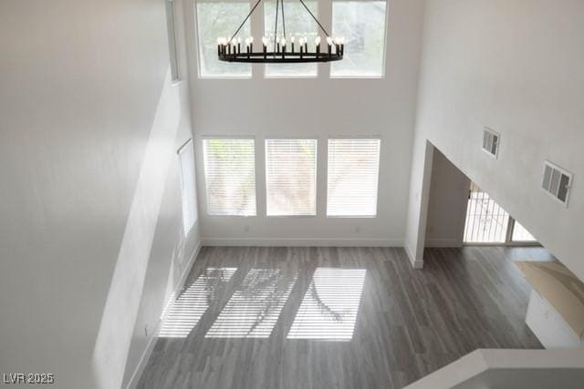 3686 Lincoln Rd, Las Vegas, NV 89115 - unfurnished living room with a towering ceiling, visible vents, a wealth of natural light, baseboards, and a notable chandelier
