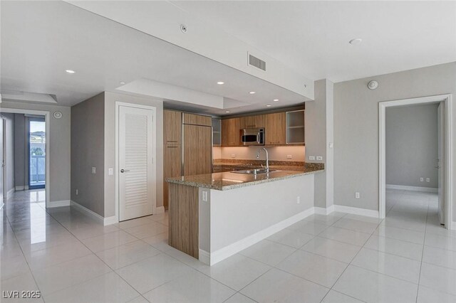 222 Karen Ave Unit 302, Las Vegas, NV 89109 - kitchen with stainless steel microwave, a sink, visible vents, stone countertops, and brown cabinetry