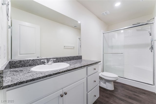bathroom featuring toilet, a stall shower, wood finished floors, and vanity