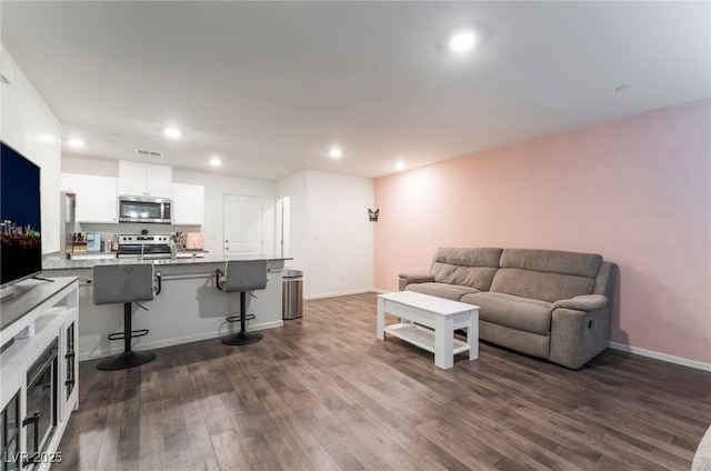living room with dark wood-style flooring, visible vents, baseboards, and recessed lighting