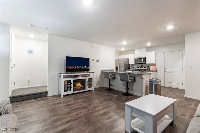 living room with recessed lighting, baseboards, and dark wood finished floors