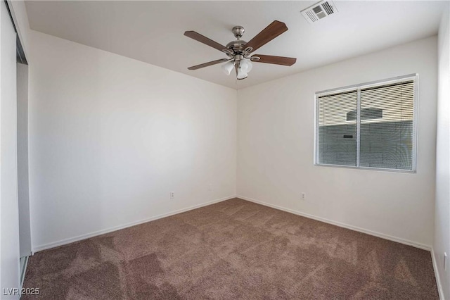 carpeted spare room with visible vents, baseboards, and a ceiling fan