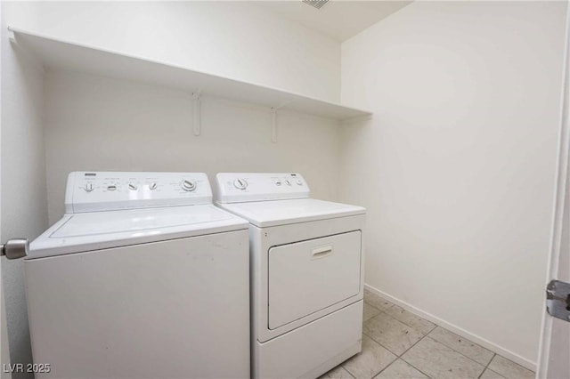 laundry area with baseboards, washer and dryer, light tile patterned flooring, and laundry area