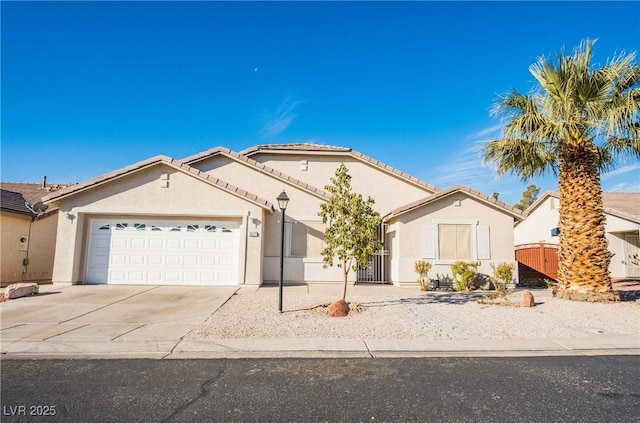 single story home with concrete driveway, an attached garage, a tile roof, and stucco siding
