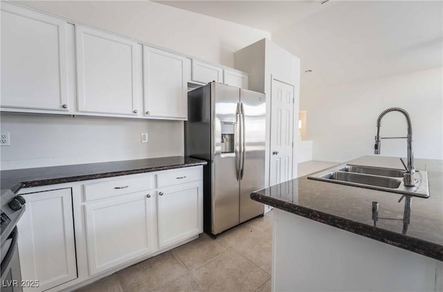 kitchen featuring stove, a sink, stainless steel fridge, and white cabinets